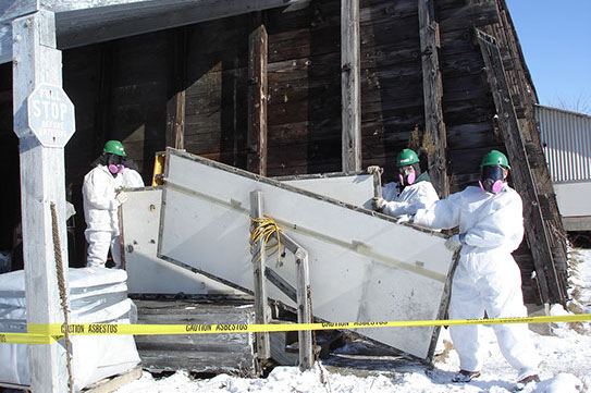 Workers moving hazardous materials out of a building