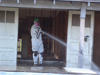 Man in hazmat suit washing out a building